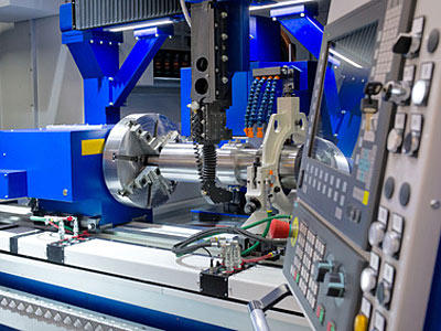 Bild einer modernen CNC-Maschine mit Steuerpult und bearbeitetem Metallteil.